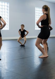 Young student following the teacher in circle time, working on her plié