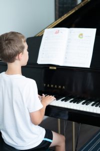 A student reads their sheet music while playing piano in rehearsal.