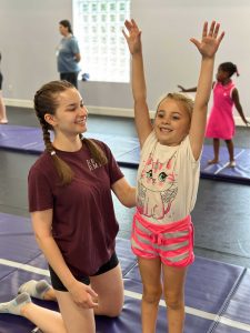 Miss Reegan spots a student preparing for a back bend at Summer Camp